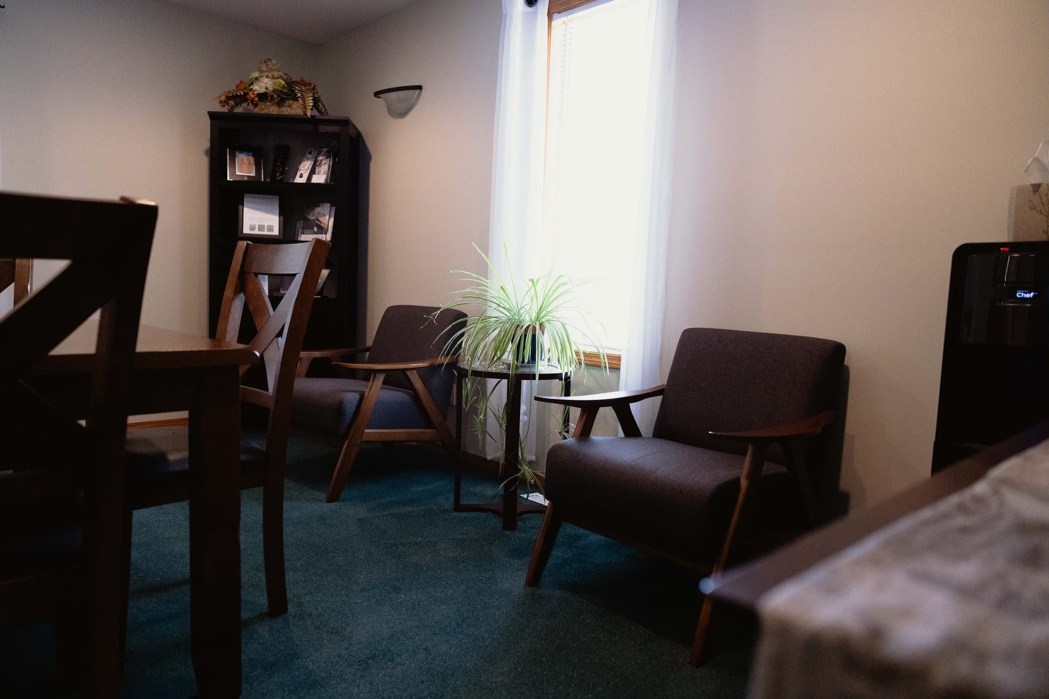 A cozy arrangement-room corner at Athabasca Community Chapel with armchairs and a keepsake cabinet, where families discuss service options