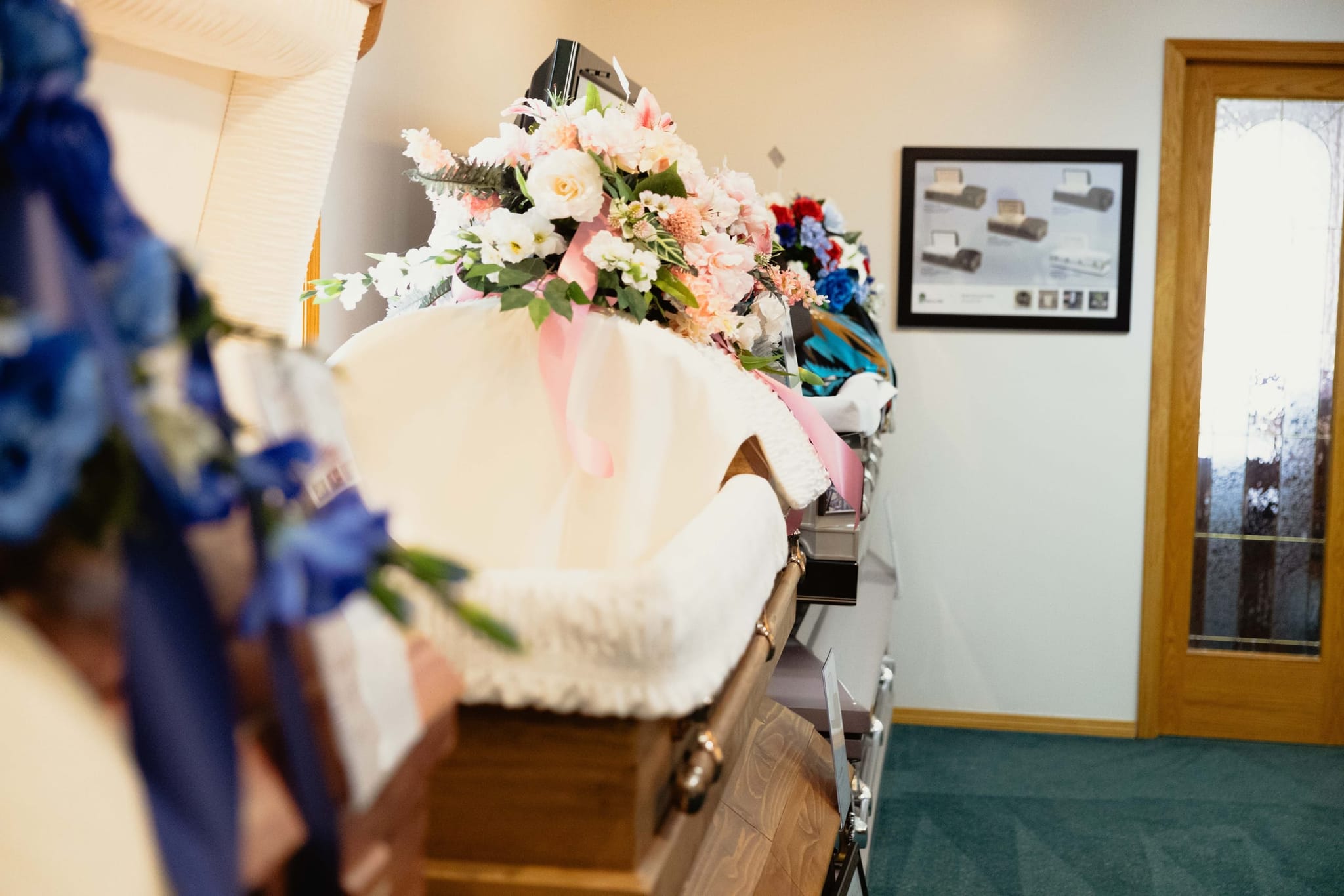An open casket dressed with a pink-and-white floral spray, prepared with care at Athabasca Community Chapel in Athabasca.