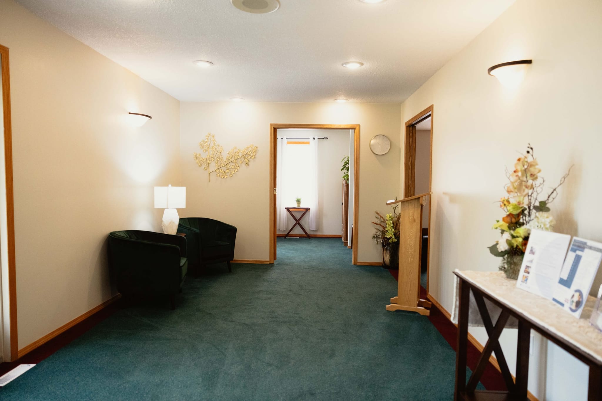 The foyer at Athabasca Community Chapel, with armchairs, a lamp, and a lectern beside the doorway through to the chapel.